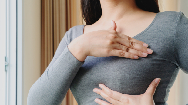 Woman hand checking lumps on her breast for signs of breast cancer. Women healthcare concept.