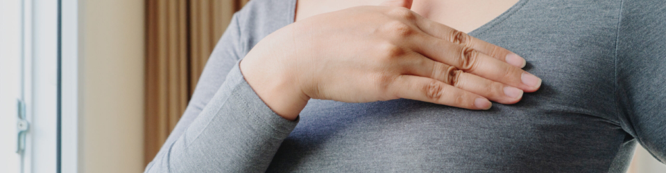 Woman hand checking lumps on her breast for signs of breast cancer. Women healthcare concept.